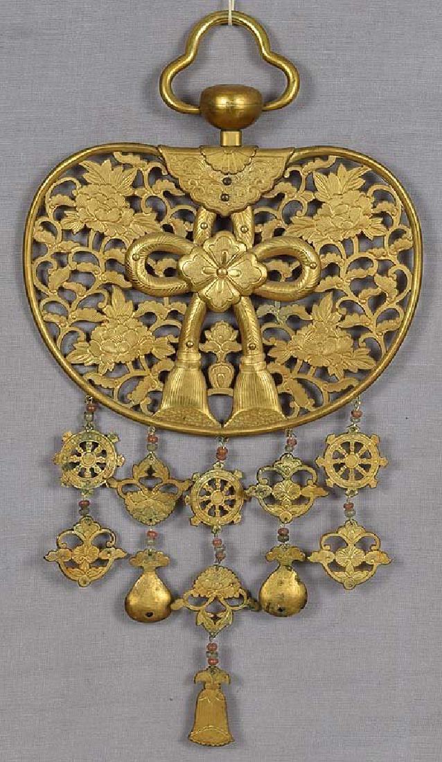 Japanese Bronze Keman Buddhist Temple Hanging, 19th C: 19th century Japanese gilded bronze keman in a shape of a rounded fan (uchiwa) with pierced decoration of flowering peonies and an elaborate knot. Hanging pendants representing the Wheel of the Buddhi