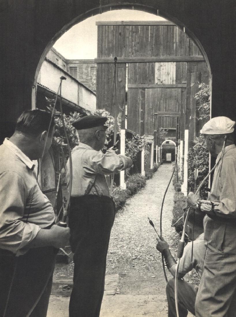 WILLY RONIS - Archery Practice, Rue des Rigoles: Artist: WILLY RONIS Print Title: Archery Practice, Rue des Rigoles Printing Date: 1954Medium: Sheet-fed Gravure Printed by Braun et Cie in France Image Size approx. 8" x 10.5" Willy Ronis (1910-2009)