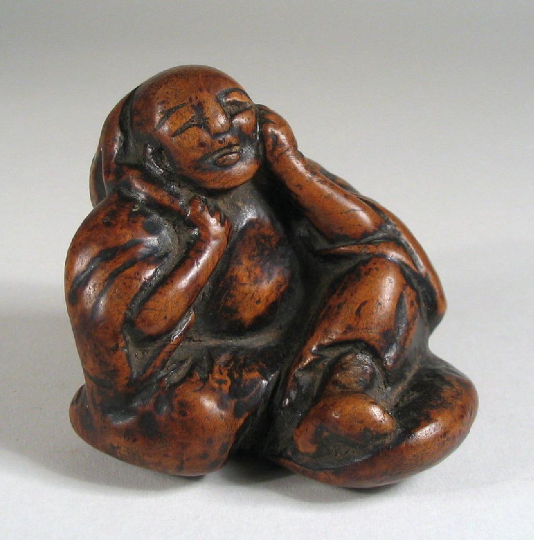 Big Chinese Burl Toggle, Seated Man, 18th/19th C: A wonderful old Chinese toggle crafted from burlwood in the form of a seated man, his head resting on one hand and the other holding a large bag over his shoulder. This larger sized toggle would have 