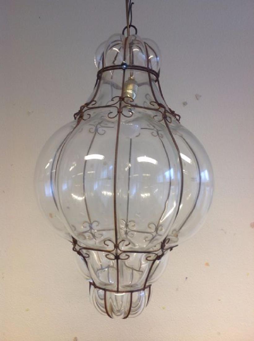 Large Murano Glass Caged Lantern: Murano Venezia Mid-century Glass, iron height 66 cm, diameter 39 cm, chain 50 cm A large Murano glass handblown lantern in the manner of Seguso in clear glass with a forged iron cage structure. Sticke