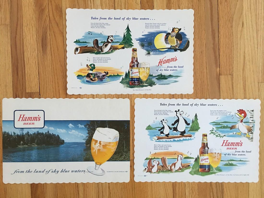 SET of THREE VINTAGE HAMM’S BEER PLACEMATS: SET of THREE VINTAGE HAMM’S BEER PLACEMATS. Each depicting seenes from the north woods and Hamm’s Beer. Brewerania. About 14 x 10. Please note that this lot has a confidential reserve. When you le