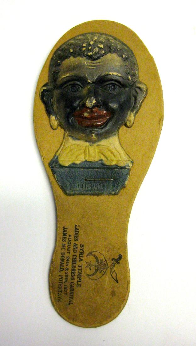 Syria Temple Carnival 1927 Negro Noisemaker: When shaken the 2 paper faces slap the handle and make a racket. Shows little wear. 6.5". Please note that this lot has a confidential reserve. When you leave a bid in advance of the auction, submit y