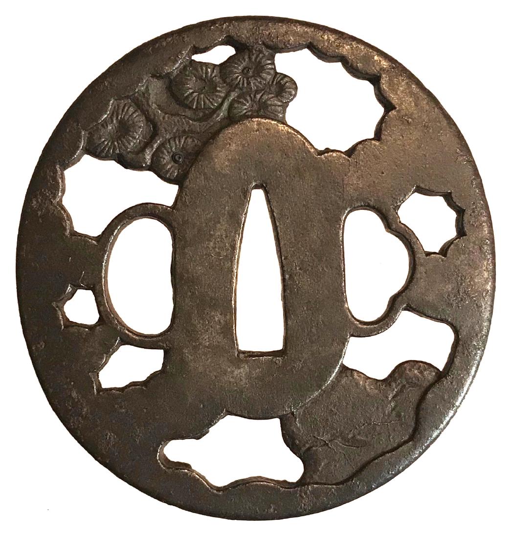 Iron sukashi tsuba with pines motif: Item: Iron sukashi tsuba with pines motif Origin: Japan Date: Edo period Materials: Iron Dimensions: 62.9 x 59.8 x 4.3 mm Iron tsuba of elongated round form. Peirces and carved with waves, clods and p