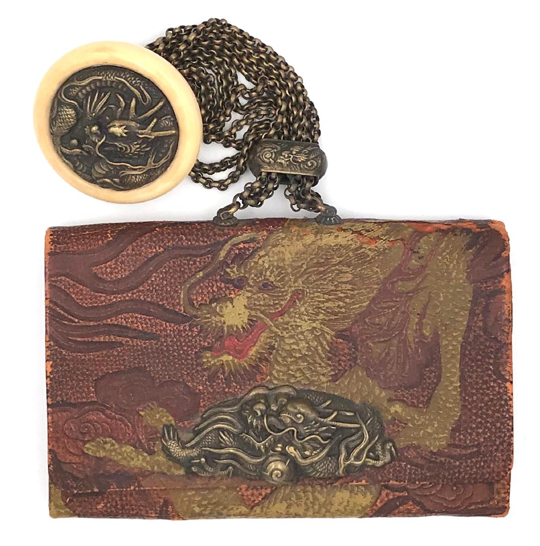 Tobacco-pouch (doran), kagami netsuke and ojime; the: Item: Tobacco-pouch (doran), kagami netsuke and ojime; the kanamono with design of dragon Origin: Japan Date: Edo/Meiji Materials: Celluloid, brass, leather Dimensions: 138 x 90 x 20 Tobacco pouch mad