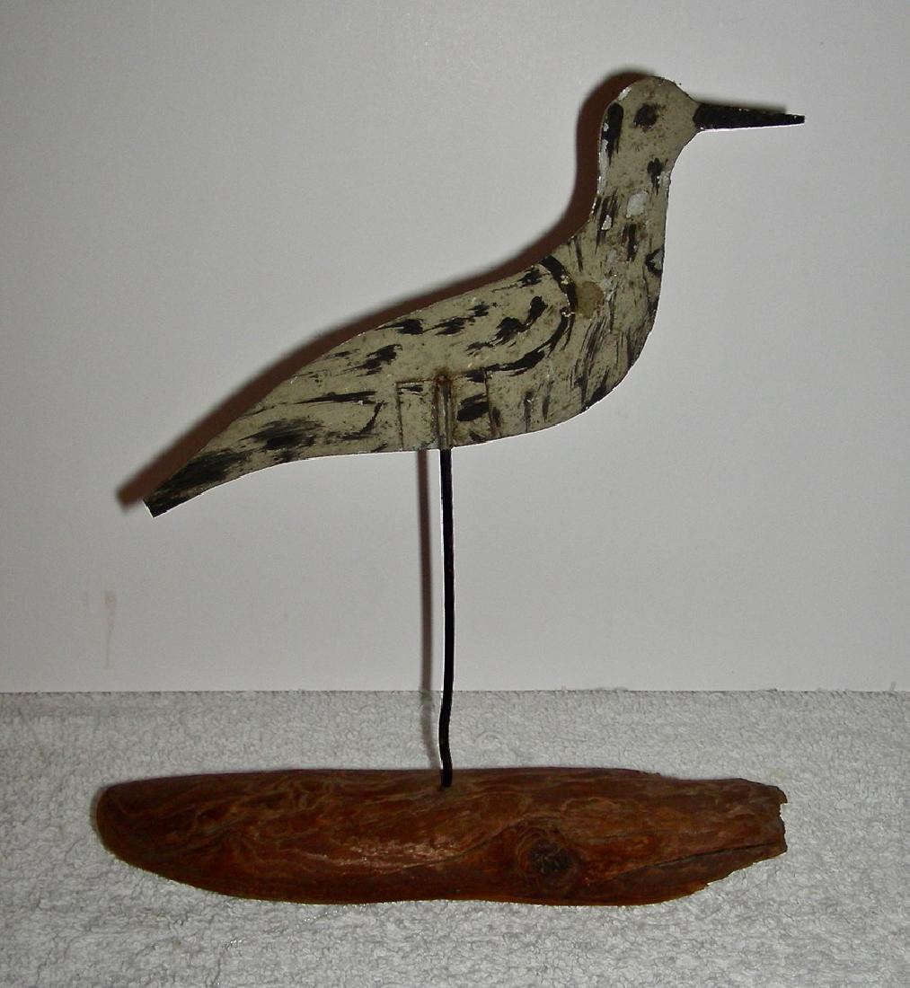 Small Decorated Tin Shorebird Decoy: A very small, painted tin Shorebird Decoy mounted on a small piece of driftwood. The bird could be one of any of a number of species, and my guess is that it is just a "generic" shorebird. Gray underc