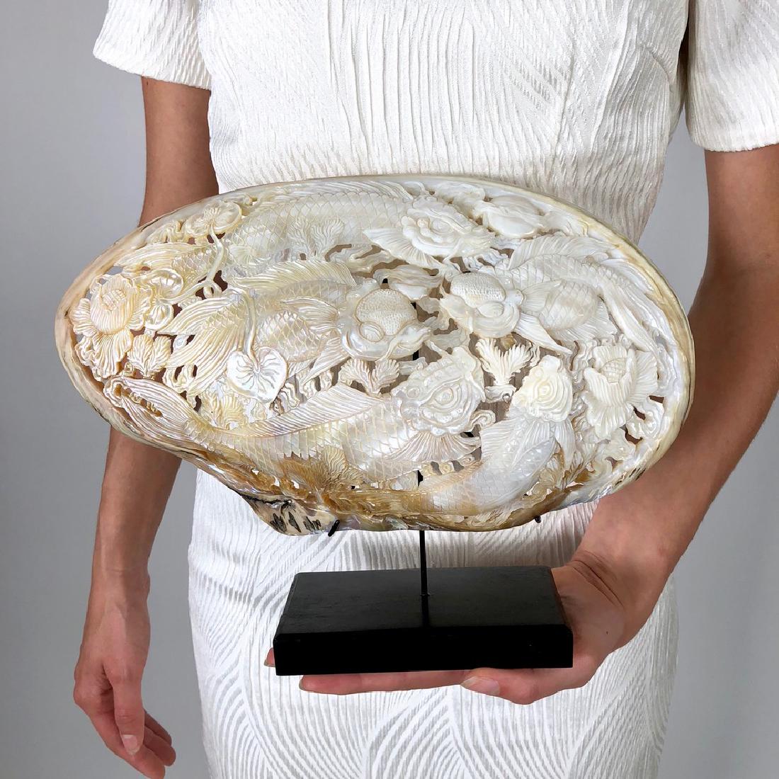 Giant engraved mother of pearl shell - Japanese KOI: Title: Giant engraved mother of pearl shell - Japanese KOI Fish engraving Maker: Design: Jake Richmond Origin: Indonesia Date/Period: 2016 Materials: Shell, Wood Dimensions: Height including stand 23