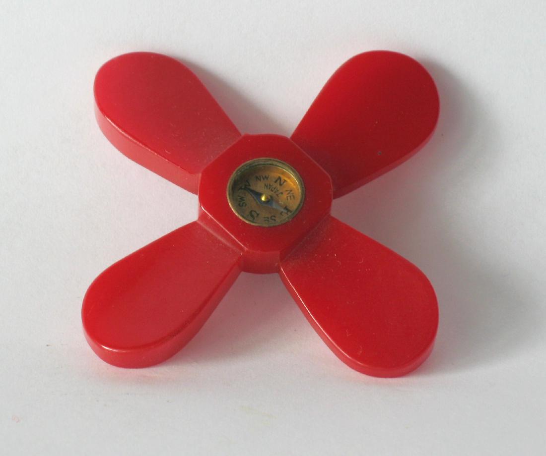Vintage Bakelite Propeller Pin: Vintage bakelite propeller pin. Date: 1930's Dimensions: 2 1/2” Provenance/Additional Information: Nice vintage pin with compass in red bakelite. Please note that this lot has a confidential reserve