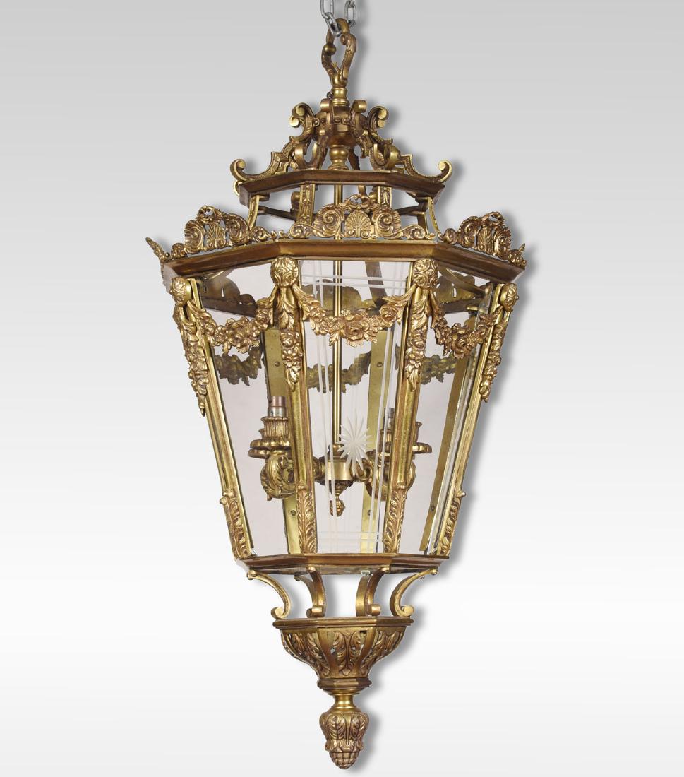 Large brass octagonal cut glass four light lantern: New to Jasper52 Very large brass lantern, of octagonal tapering form. The shell and leaf scroll crestings. Over floral swags with engraved glass panels, enclosing four light fittings. The canopy surmo