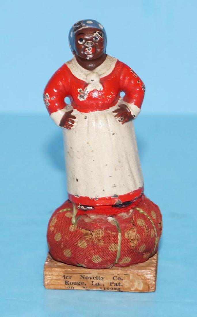 Mammy Cast Iron Pin Cushion Hubley Paperweight: A Vintage Cast Iron Mammy Pin Cushion. Mammy made by Hubley. Partial souvenir label reads, "Novelty Co., Rouge, LA., Pat. No 113226, Marblestown". Great addition to a Black Americana collection. Measu