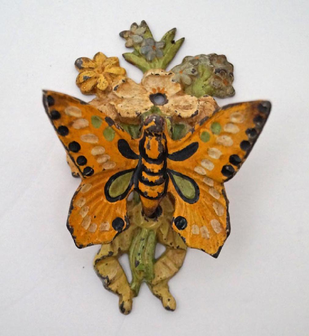 Butterfly on Flowers Cast Iron Doorknocker: An Antique Butterfly Cast Iron Doorknocker. Showing butterfly on array of mixed flowers arranged and tied with a bow. Hard to find form. Measures 4” tall x 2 3/8” wide. Circa 1920’s. Shipping: D