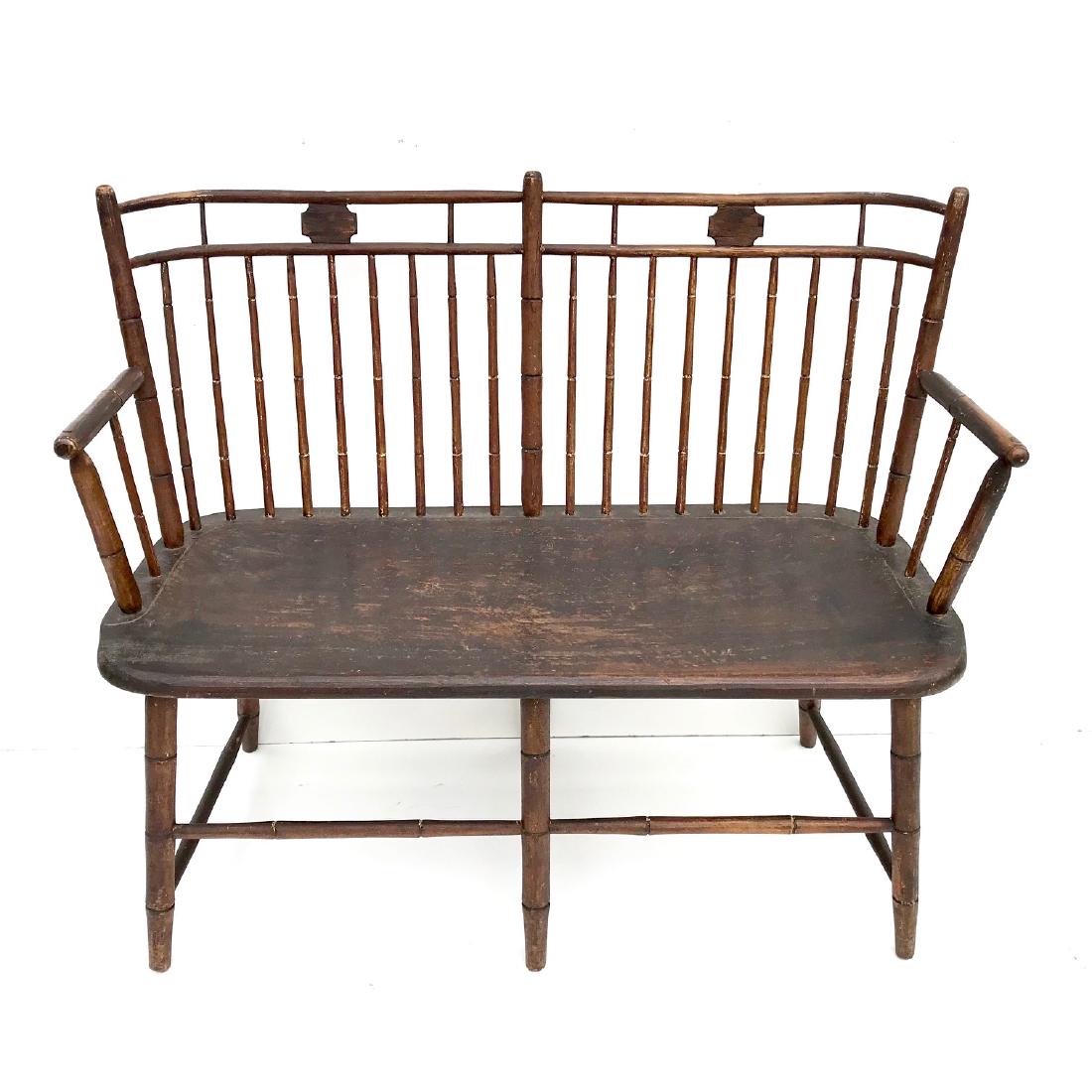 Windsor “Love Seat” Settee: Early, two-person, windsor settees are scarce. This one, which has butterfly medallions, also offers rare, curved corners in the crest rail. Century-old varnish covers traces of 19th- century mustard