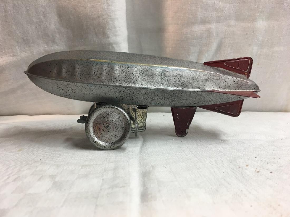 Zeppelin Wind Up Tin Toy: Title: Zeppelin Wind Up Tin Toy Date: 1940-1950 Dimensions: 10" by 3" by 4" Provenance/Additional Info: Winding mechanism works. Needs traction. Speckled surface Shipping: Domestic: Flat-rate of $15.0