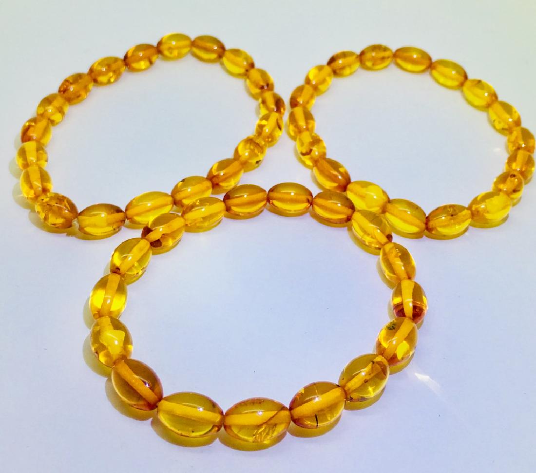Three Amber bracelets from honey coloured olive shaped: Title: Three Amber bracelets from honey coloured olive shaped beads Gemstones: Amber Weight: 16.2 g Size: 10.2 x 6.8 mm beads Additional Information: Honey colour beads Reserve: $35.00 Shipping: