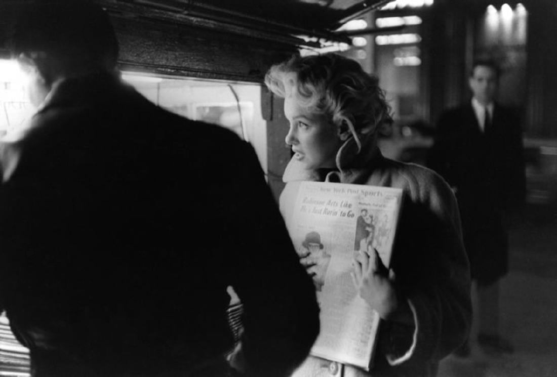 Marilyn Gets The Paper: Artist: Ed Feingersh Title: Marilyn Gets The Paper Medium: Silver Gelatin Year: 1955 Height/Width: 16x20 in Description: Actress Marilyn Monroe picks up a copy of the New York Dail Post newspaper at a