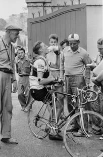 British Rider On Tour: Artist: Bert Hardy Title: British Rider On Tour Medium: Silver Gelatin Year: 1955 Height/Width: 16 x 12 in Description: British rider Ken Mitchell stops for a drink during the Tour de France, July 195