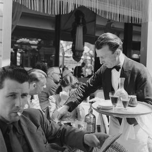 Cafe Culture: Artist: Bert Hardy Title: Cafe Culture Medium: Silver Gelatin Year: 1951 Height/Width: 30 x 30 in Description: A waiter serving clients on the terrace of a cafe on the Champs-Elysees, Paris, June
