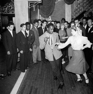 Dancing Duo: Artist: Bert Hardy Title: Dancing Duo Medium: Silver Gelatin Year: 1949 Height/Width: 12 x 12 in Description: 2nd July 1949: A crowd gathers to watch a black man dancing with a white woman on centre