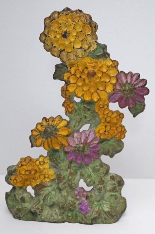 Antique Zinnias Flower Cast Iron Doorstop: Title: Antique Zinnias Flower Cast Iron Doorstop Date: Circa 1920's. Dimensions: 9 5/8" tall x 5 3/4" wide. Provenance/Additional Information: Antique Zinnias Flower Cast Iron wedge Doorstop. Nice col
