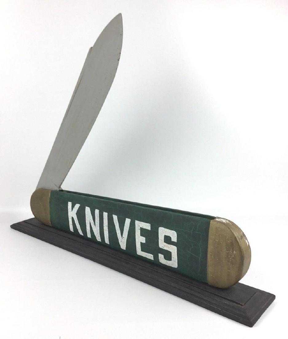 Wood Carved Knife Trade Sign: Title: Wood Carved Knife Trade Sign OLD WEATHERED SURFACE WITH NO RESTORATION. THE BLADE IS FIXED. IT IS 27" WIDE X 20" TALL. MOUNTED ON A CUSTOM BASE AND CAN BE REMOVED. IT HAS A FREEPORT, MAINE HIST
