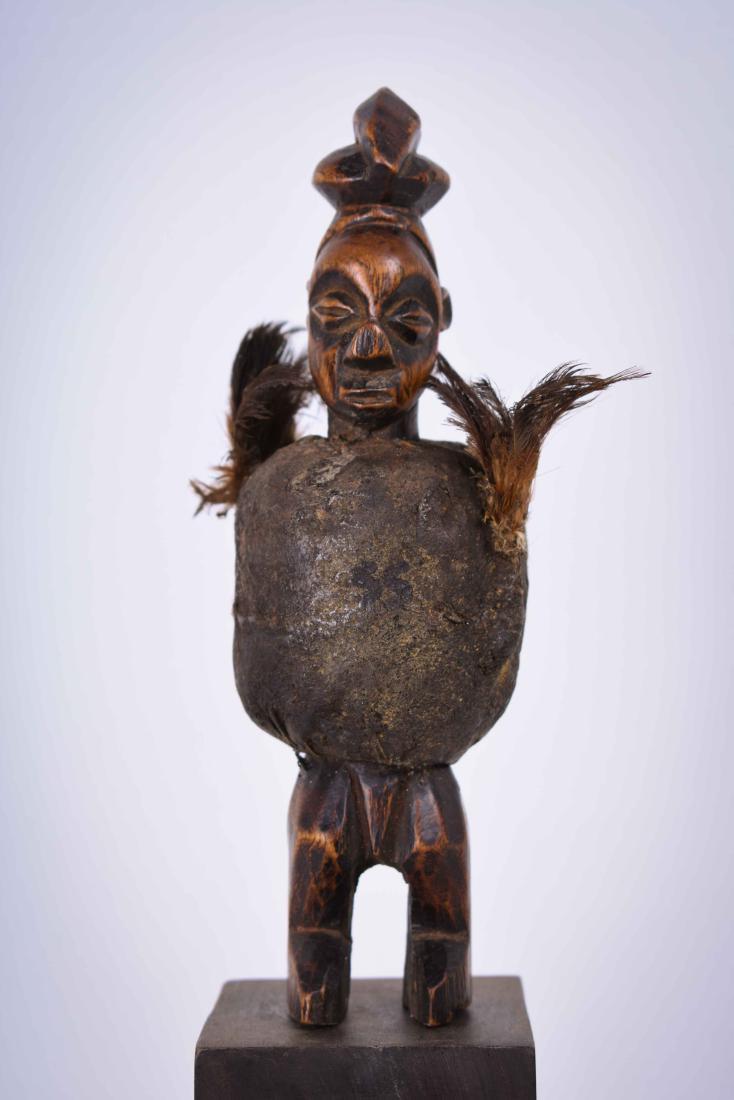 Fetish Figure – Magical Substances, Wood – Buti – Yaka: The majority of Yaka figures were associated with Mbwoolo shrines. Their abdomen are hollow, enabling the insertion of fetish material and they are also adorned with bundles of paraphernalia. Yaka fig