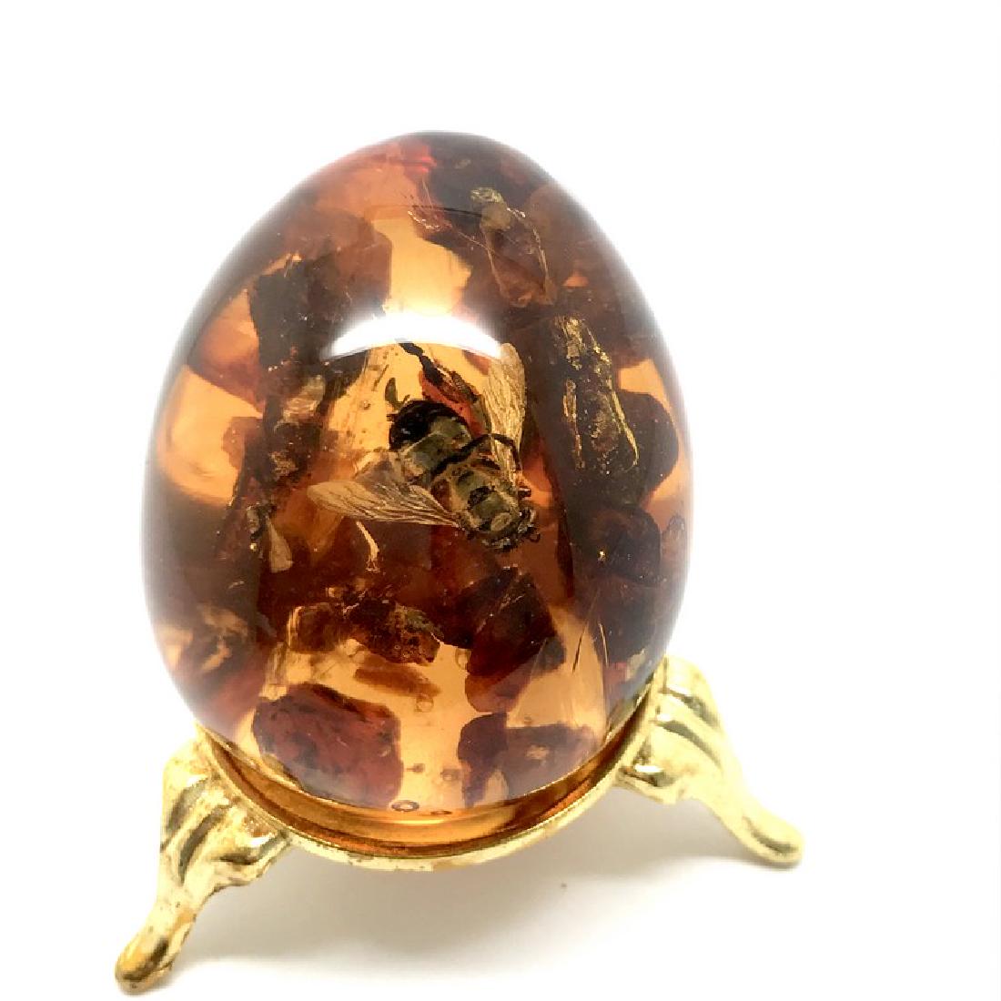 Amber egg with bee insect inclusion, on the stand (1 of 7)