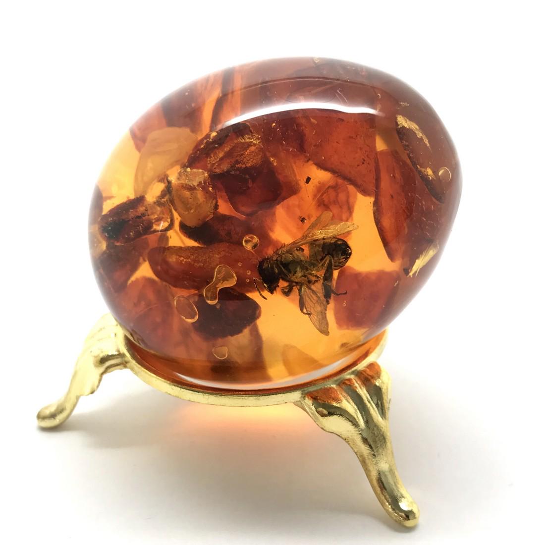 Amber egg with bee insect inclusion, on the stand (1 of 7)