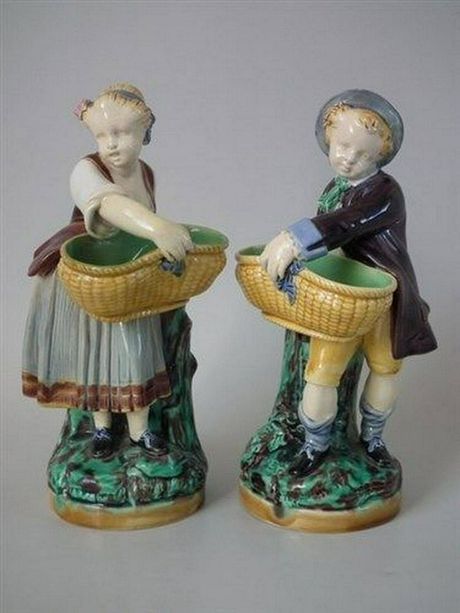 Pair Minton Majolica boy/girl with basket figures: Title: Pair Minton Majolica boy/girl with basket figures Description: Pair Minton Majolica boy/girl with basket figures Description Pair of Minton Majolica figurals which feature a boy and girl each h