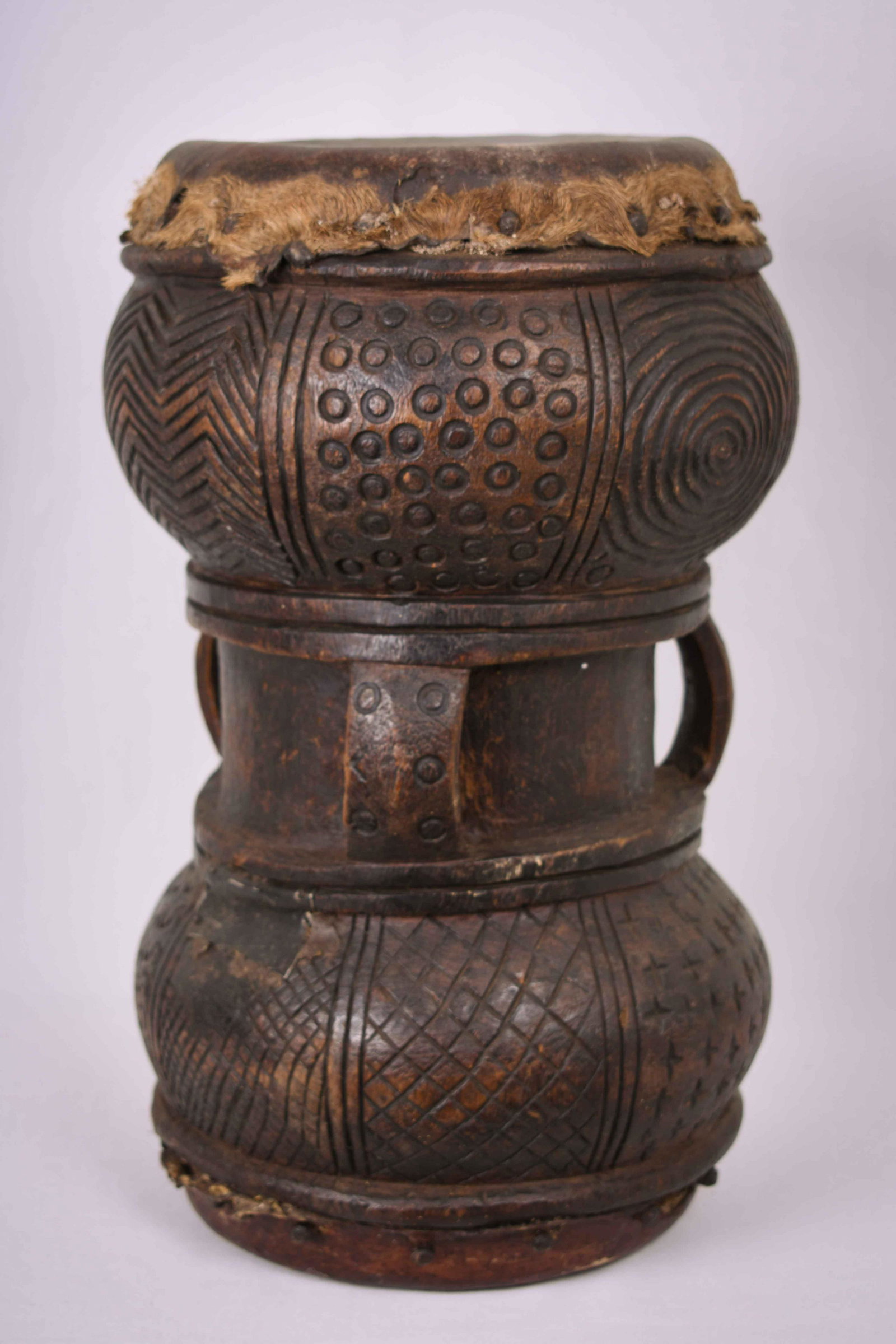 Mukupiela Drum – Leather, Wood – Chokwe – Dr Congo: The Mukupiela is a drum of the Chokwe people, who dwell in the extensive and fertile border area between Angola and the Congo. The mukupiela is an important attribute of the Chokwe kings. It is heard 
