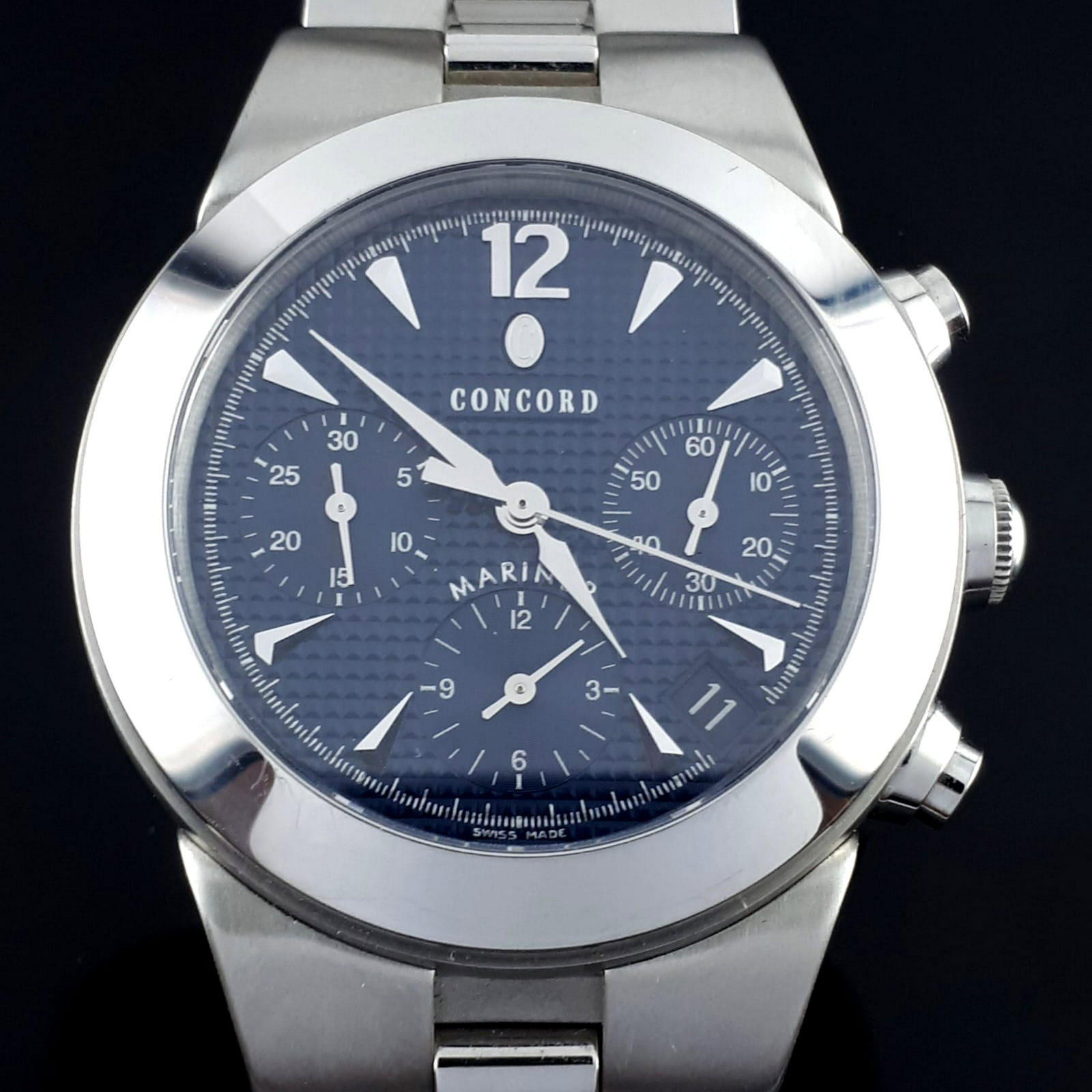 Concord - Mariner Chronograph Automatic Blue Dial - Men: The case has a polished stainless steel Bezel and Crown. The frame is circular and is 38mm in diameter. Meanwhile it has a transparent push down back plate to insure the watches durability and to disp