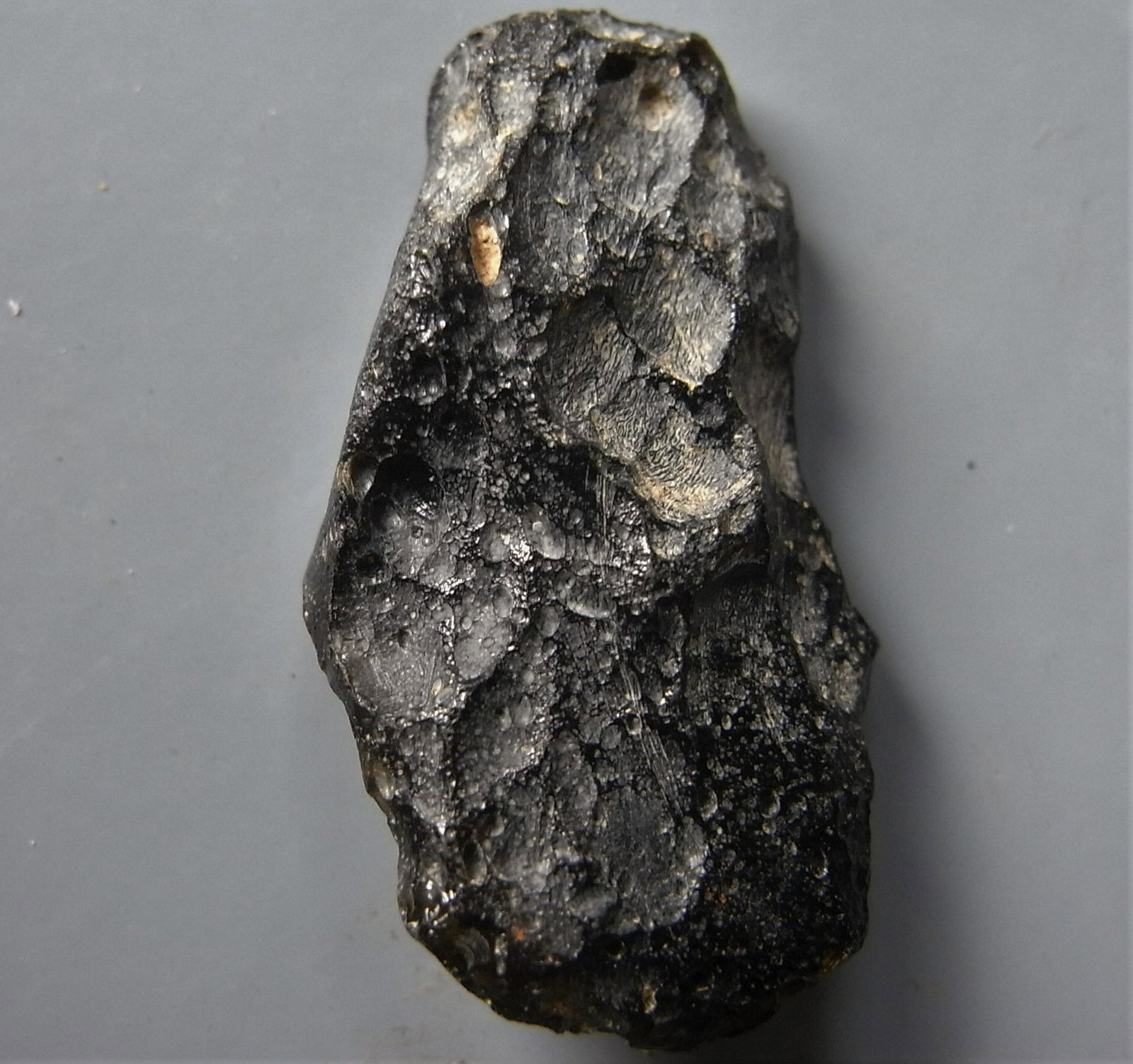 THAILANDITE TEKTITE - FROM METEORITE IMPACT: Title: THAILANDITE TEKTITE - FROM METEORITE IMPACT Origin: Noen Sa-nga. Chaiyaphum Prov. Thailand Size: 2.7x1.5x0.6 cm / 4 gram Description: flat, irregular shaped, pitted thailandite tektite. tiny gl