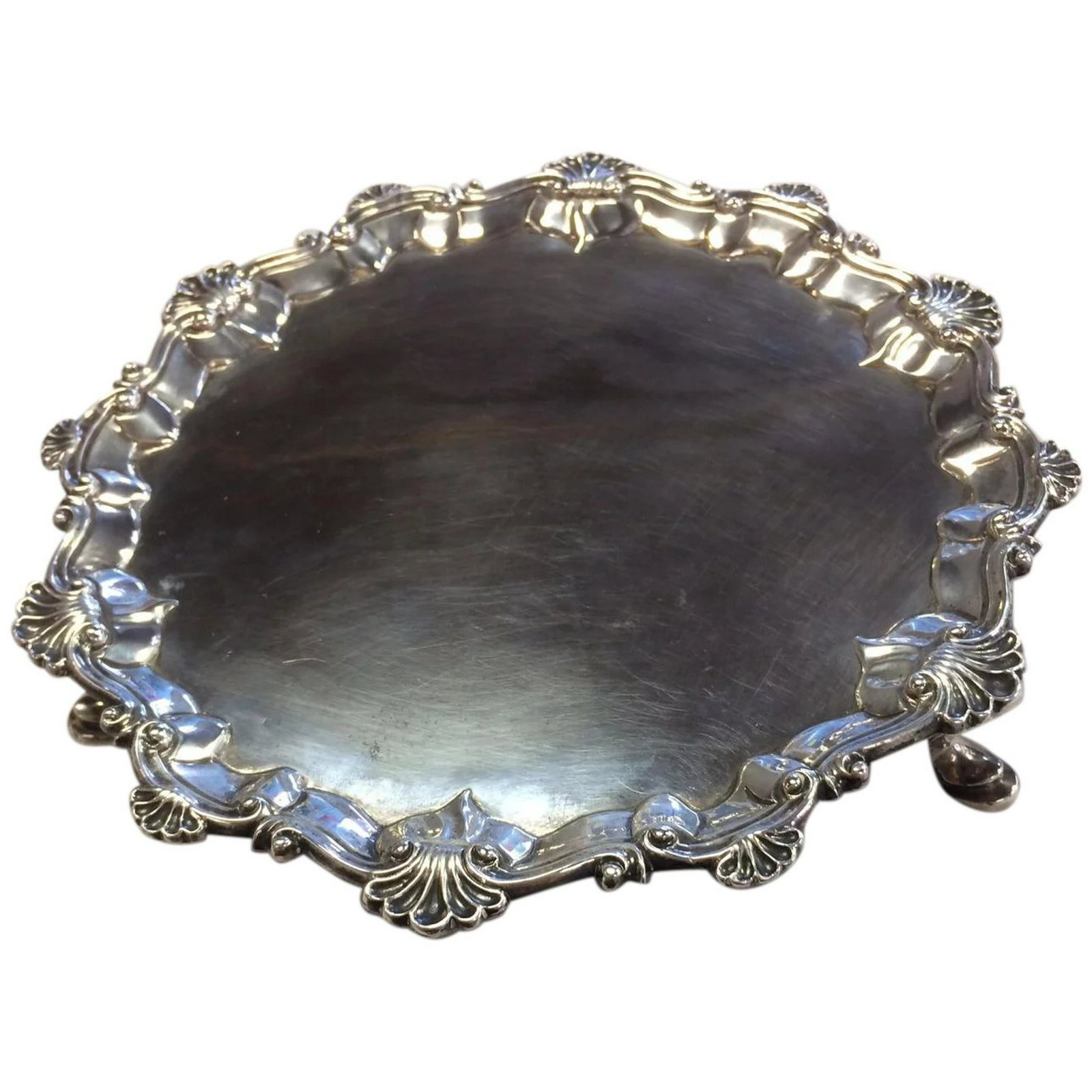 London 1768 Sterling Salver or Waiter 7 1/8" Diameter: Small English sterling silver salver or waiter, approximately 7 1/8 inches in diameter with scrolls and shells border and stands on three pad feet. English hallmarked for being made in 1768 London by 