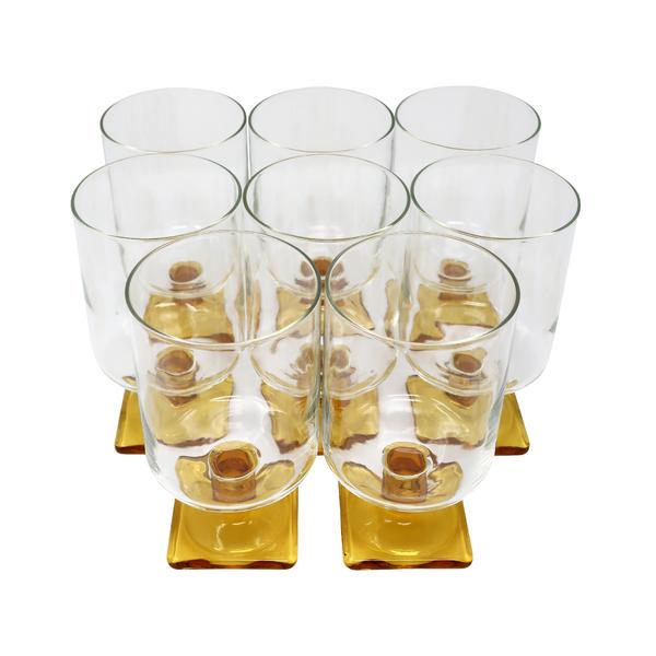 Set of Eight Vintage Butterscotch Drinking Glasses: A set of eight mid-century modern drinking glasses with clear bodies and beautifully golden butterscotch colored square base. 12” x 6” x 4.5” Reserve: $70.00 Shipping: Domestic: Flat-rate of $20