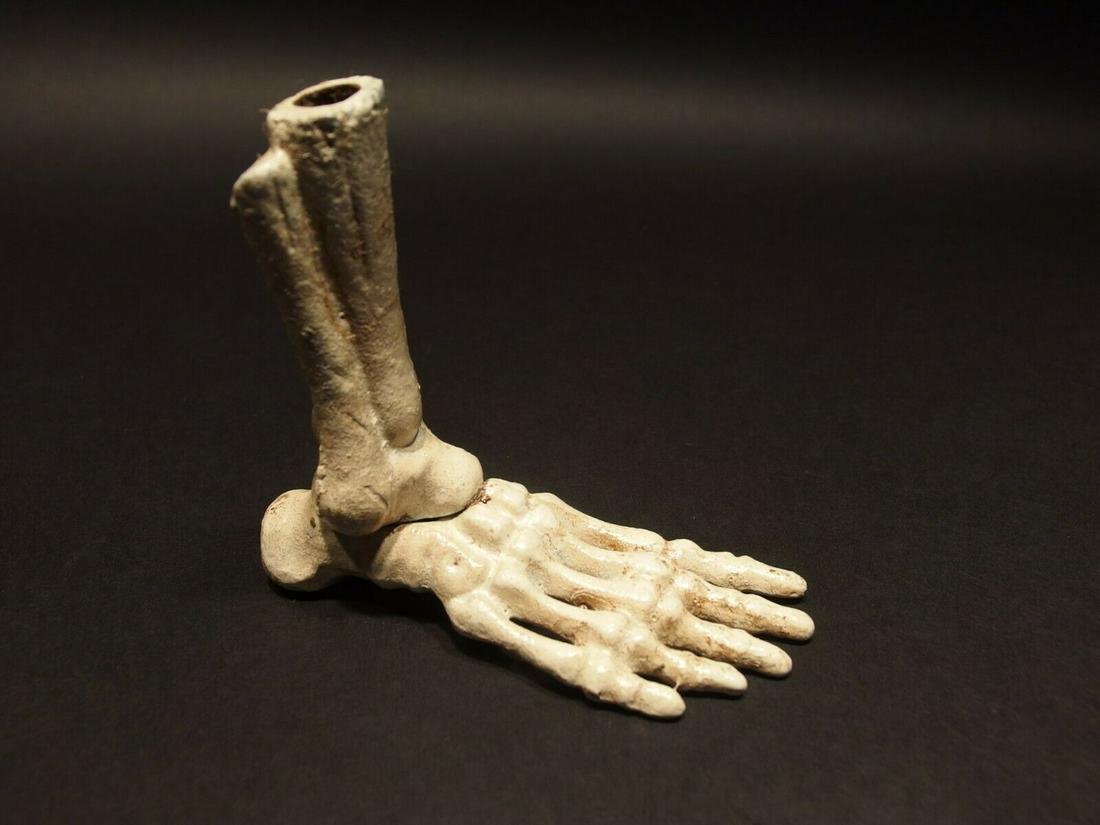 Cast Iron Skull Skeleton Foot Pen Holder: 4" tall x 4 1/2" long Such neat reproduction antique cast iron skeleton foot pen holder. Wonderful solid iron hand painted and distressed piece. The leg bone of the skeleton foot has a small hole to p