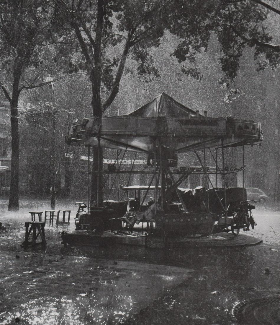 ROBERT DOISNEAU - Carousel in the Rain: Artist: ROBERT DOISNEAU - Print Title: Carousel in the Rain Printing Date: 1950’s Medium: Photoengraving Printed in: The UK Image Size approx.: 9 x 7.5” Robert Doisneau (1912 – 1994), was a Fren