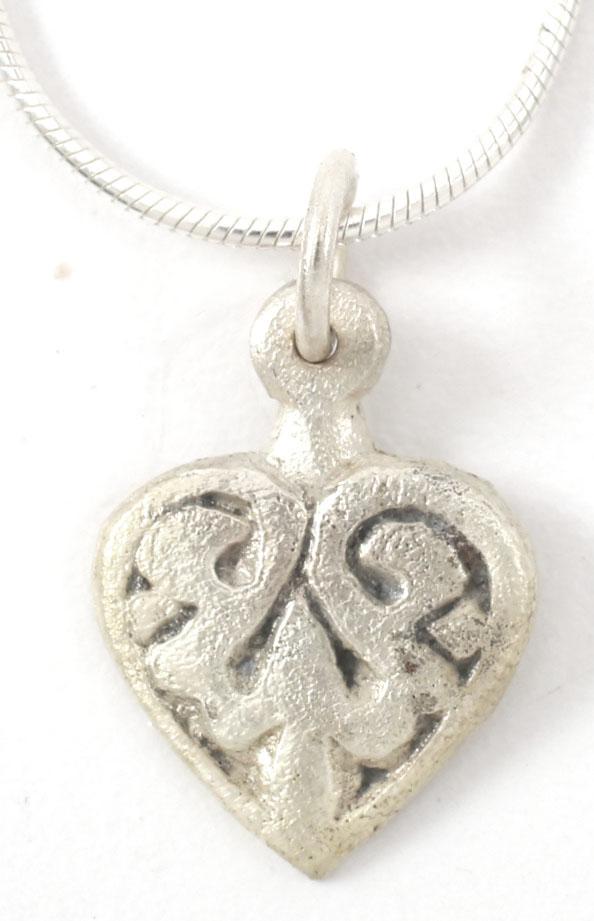 VIKING HEART PENDANT C.900-1000 AD.: Early example of the fully evolved form with cusped top and near rounded sides. Slightly domed with large central trefoil motif, the upper members comprising the scrolled border terminal. Just over 3/