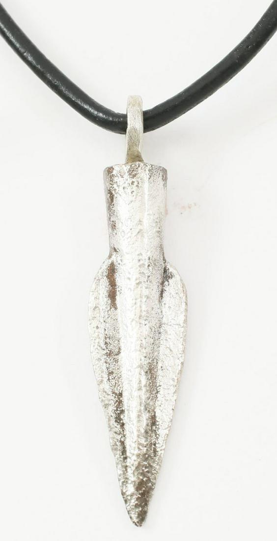 FINE GREEK ARROWHEAD PENDANT 650-330 BC.: 1 3/8Â” length. Conical with two rounded veins Surface textured from burial. Professionally refurbished with silver overlay and mounted on a modern polished leather neck cord for contemporary wear.