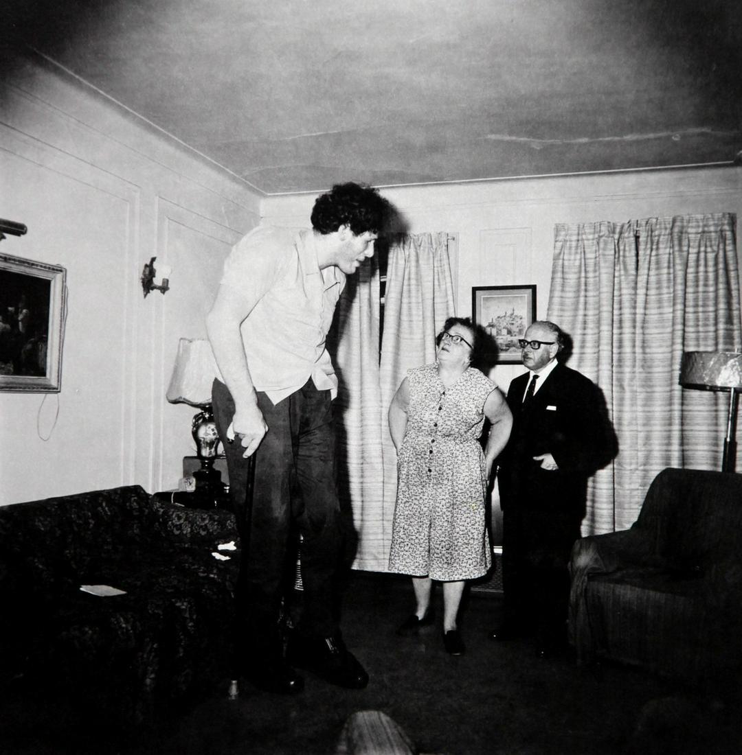 DIANE ARBUS - A giant at home with parents in the Bronx: Artist: Diane Arbus Title: A giant at home with parents in the Bronx 1970 Date Printed: 1979 Medium: Heliogravure Printer Location: Italy 25 x25 cm - 10x 10 inch, Mount Size: 30x40 cm - 15.7x11.8 Inch