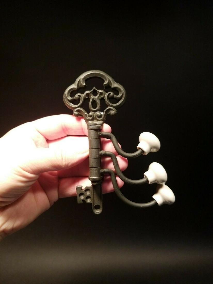Cast Iron Key Swivel Hook W Porcelain Knobs: 5 1/4" Tall 4 1/2" max extension Such a classy reproduction folding wall hook! The intricate key design and the porcelain nobs make it such a neat piece. As you can see the hooks swivel and fold out o