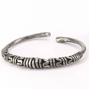A TWISTED SILVER BANGLE: A TWISTED SILVER BANGLE; A silver bangle consisting of a silver rod twisted back on itself in spirals and zig – zags. This style of ornament is well known from finger rings but bracelets of this