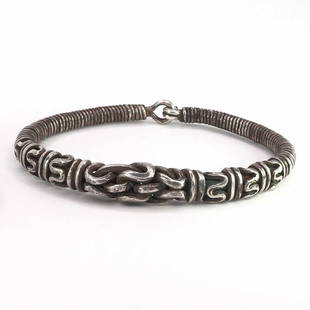 A Twisted Silver Bangle: A Twisted Silver Bangle; Two silver bangles consisting of a silver rod twisted back on itself in spirals and zig – zags. This style of ornament is well known from finger rings but bracelets of this