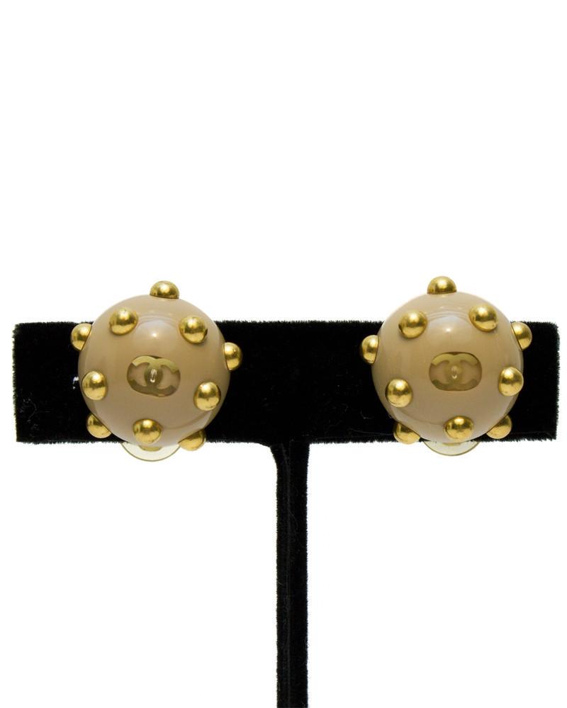 Chanel Beige Studded Earrings: These Chanel clip-on earrings from the Autumn 2000 collection are beige resin with gold tone studs, and a small CC logo in the center. Stamped with Chanel A 00 on the back. Excellent vintage condition