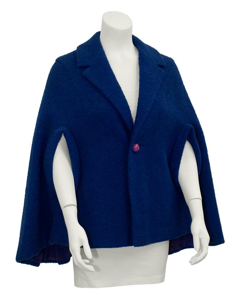 Anonymous Blue Wool Cape: This anonymous blue boucle wool cape dates from the mid 1950's. It features a notched collar with a single button closure at center. Pink sphere button adds an adorable pop of color. A-line shape with