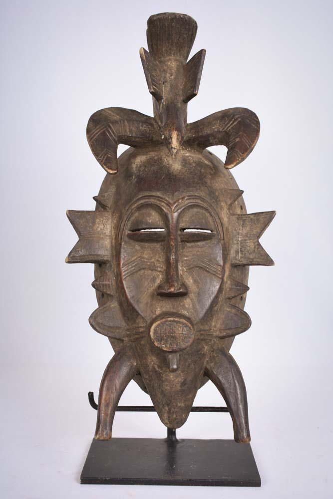 Kpeliye Mask – Wood – Senufo – Ivory Coast: Stylistic wooden mask from the Senufo people of Ivory Coast. The unique features which characterize the Kpelie mask include elongated flanges radiating from the bottom part of the mask, which are a re