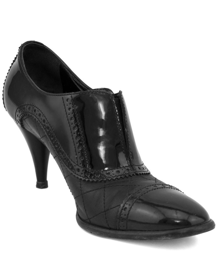 Chanel Black Brogue Pumps: 1990s Chanel black brogue pumps with quilted leather body and black patent leather accents. Broguing details throughout and tiny CC on the outer heel. In excellent condition with some signs of wear to