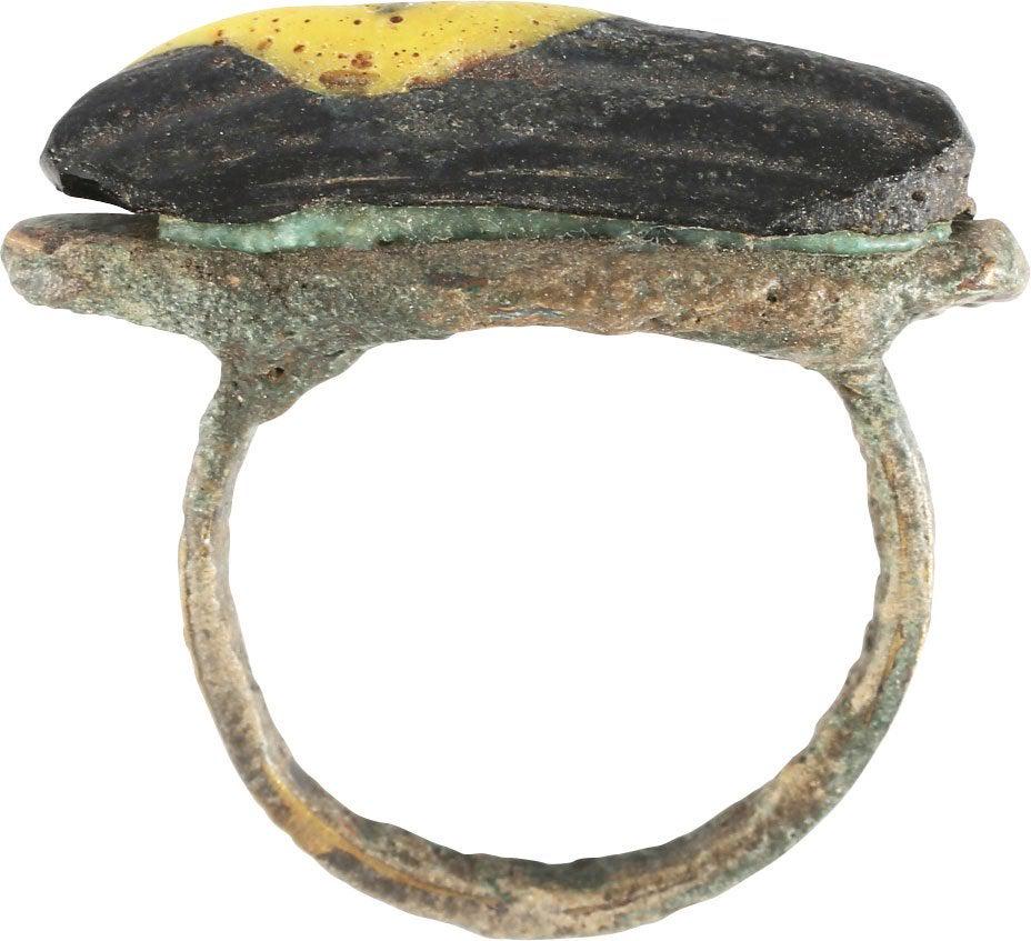 ANCIENT MEDIEVAL PEASANT’S RING SZ 7 1/2 JEWELRY: 7th-12th century. Primitive provincial example with bronze band and integral bezel of oversize elongated oval shape. The top with a lamp work yellow on blue glass “stone”. Crude and garish in as f