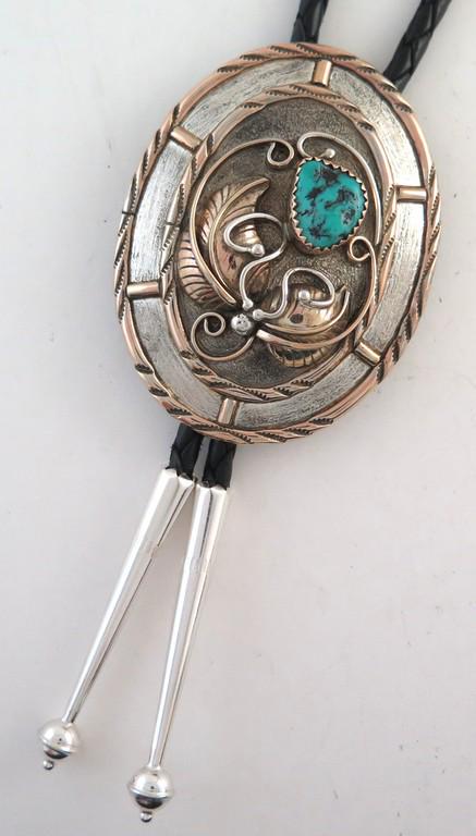 Sterling Silver Gold Filled Appliqué Bolo Tie: Title: Sterling Silver Gold Filled Appliqué Bolo Tie Date/Period: 1980s Materials: Sterling Silver Dimensions: 2 & 3/16" long (5.56 cm) and 1 & 11/16" wide at its widest point (4.29 cm) Additional In