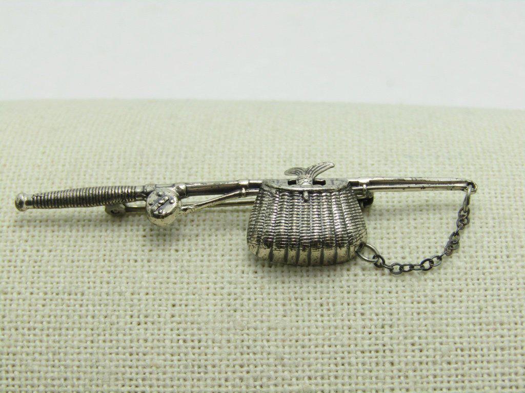 Vintage Beau Sterling Fishing Pole Brooch, Creel, Fish: Vintage Beau Sterling fishing pole Brooch with creel, complete with detailed fish tail stick out of the basket and a chain that looks like the fishing line. It is 2.5" long and 5/8" wide at the woven 