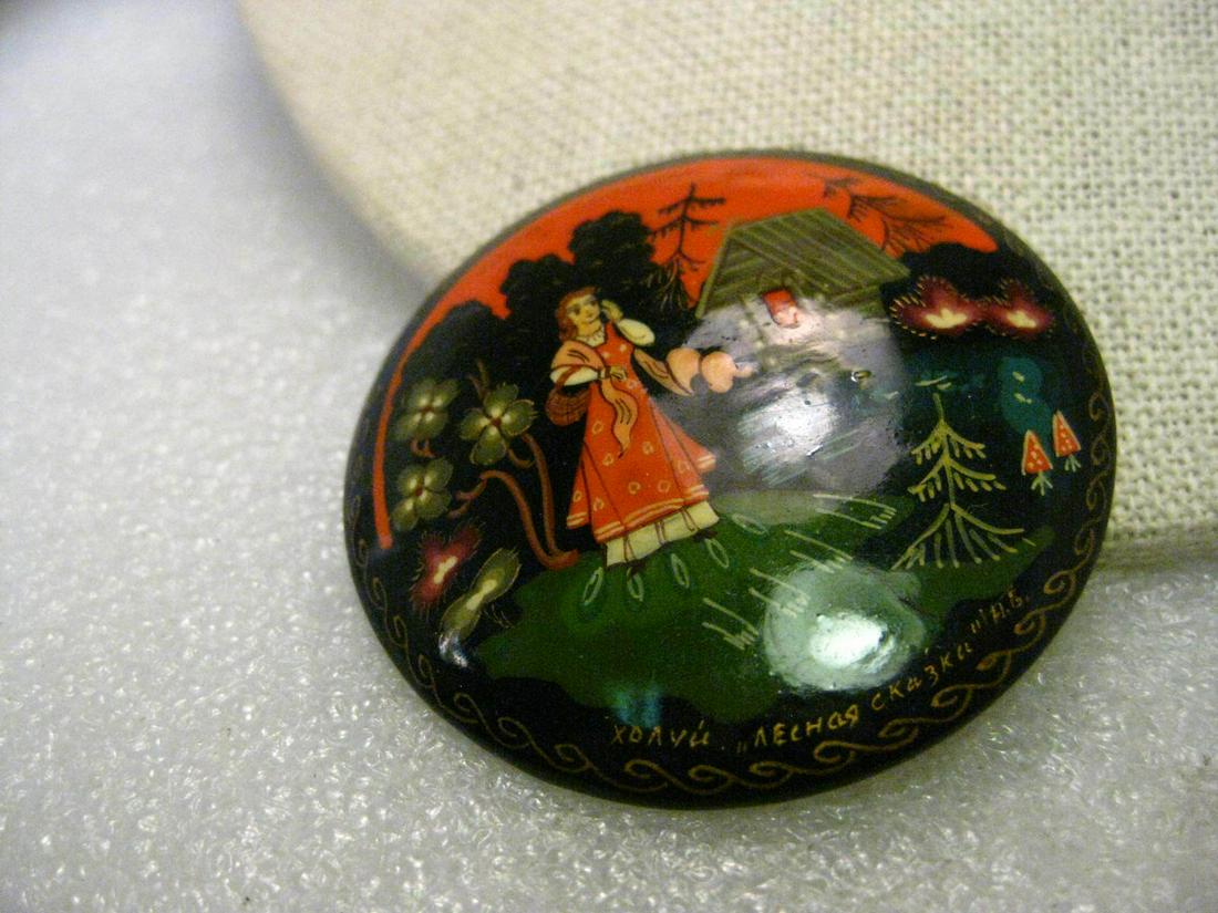 Vintage Black Lacquered Russian Hand-Painted 2" Round: Vintage black lacquered Russian hand-painted brooch - perhaps Little Red Riding Hood or a fairy tale scene. This is a woman with reddish hair and a basket over her arm walking away from a cottage with