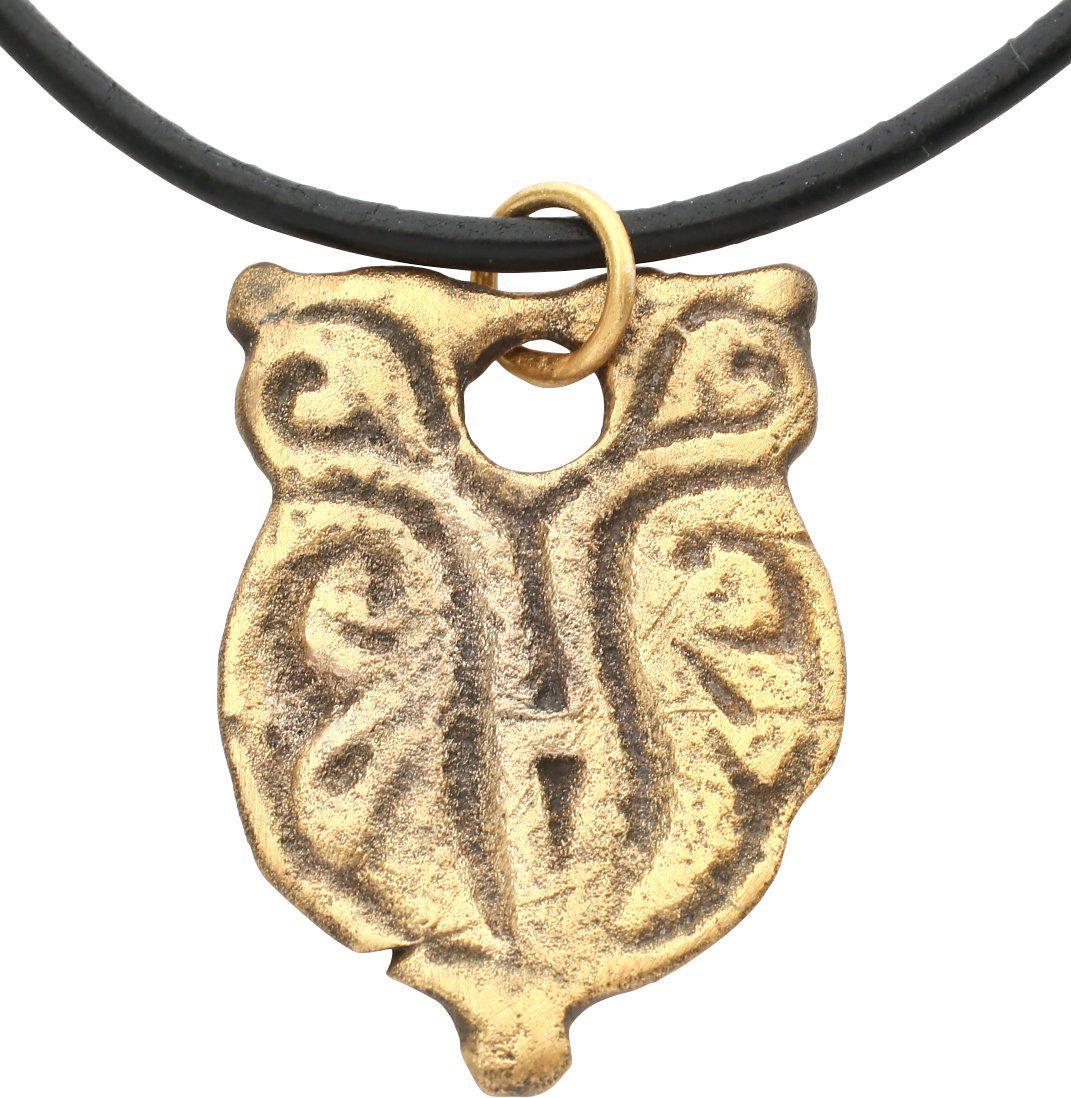MEDIEVAL WARRIOR’S PENDANT: Europe, 14th-15th century. Gilt bronze, 1 ¼” height of shield shape with symmetrical foliate decoration The top pierced with a hole for lacing to the garment. These evidently identified the noble l