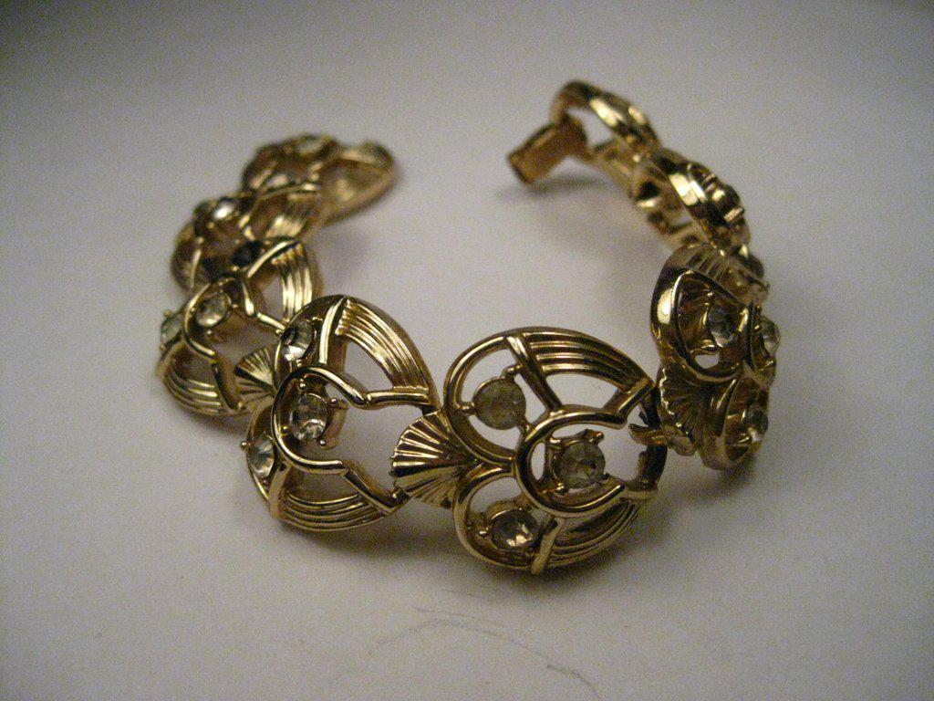 Vintage Gold Tone Coro Rhinestone Art Deco Style: Vintage Gold Tone Coro bracelet with rhinestones - 8" long, flip over clasp with rhinestones. It is about 1" wide. The 8 links have a ribbed and cut-out design with an art deco flare and a fan like pi